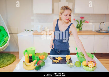 Junge lächelnde blonde Frau kochen frische Früchte in der Küche. Gesundes Essen. Vegetarische Mahlzeit. Diät Entgiftung Stockfoto