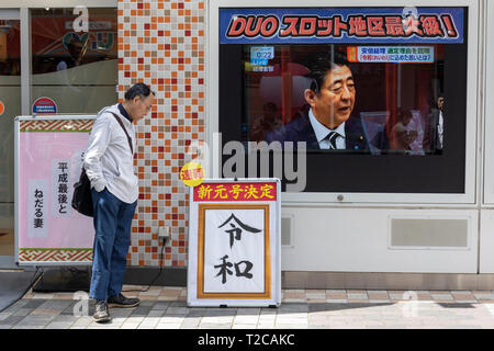 Tokio, Japan. 1 Apr, 2019. Tokio, Japan. 01 Apr, 2019. Ein Mann sieht einen Schild mit dem japanischen Kanji''Reiwa'' als neuen Namen der nächsten Kaiserzeit, in der Innenstadt von Tokio. Die japanische Chief Cabinet Secretary Yoshihide Suga angekündigt ''Reiwa'' als neue Kaiserzeit Name heute, 1. April. Die neue Ära beginnt am 1.Mai, wenn der Kronprinz Naruhito besteigt den Thron, nachdem sein Vater, Kaiser Akihito, formal dankt am 30. April. Credit: Rodrigo Reyes Marin/LBA/Alamy leben Nachrichten Stockfoto