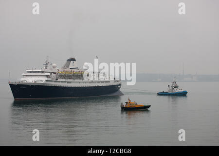 Cobh, Cork, Irland. Der 1. April 2019. Erste liner der neuen Saison Kreuzfahrt Astoria von der Tug Boat Gerry O'Sullivan während der Pilot Boot Failte watchs in Cobh, Co Cork, Irland manövriert wird. Quelle: David Creedon/Alamy leben Nachrichten Stockfoto