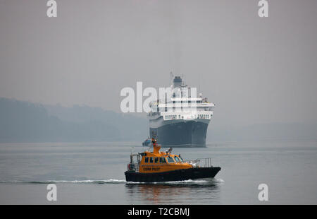 Cobh, Cork, Irland. Der 1. April 2019. Kreuzfahrtschiff Astoria kommt in einer nebligen Hafen von Cork - das ist der erste Liner in der neuen Saison und wird hier durch den lotsenboot Failte in Cobh, Co Cork, Irland begleitet. Quelle: David Creedon/Alamy leben Nachrichten Stockfoto