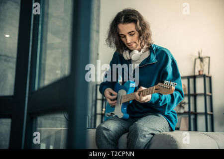 Friedliche gut aussehenden Kerl mit Tattoo auf dem Gesicht spielen auf der Gitarre Stockfoto