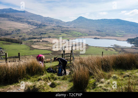 Zwei weibliche Wanderer stoppen aus Schichten zu warm auf eine Wanderung bis Y Garn auf der Nantlle Grat über Rhyd Ddu, Gwynedd, Wales, Großbritannien, Großbritannien Stockfoto