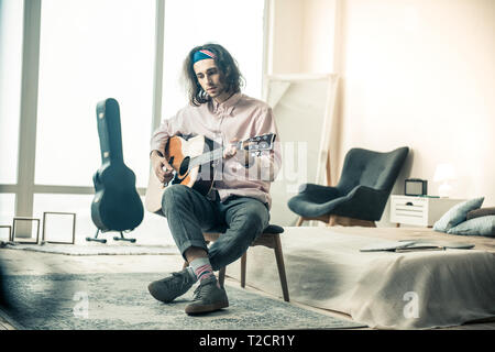 Gesund aussehenden Musiker mit gewelltes Haar spielen akustische Gitarre Stockfoto
