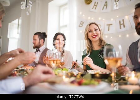 Eine glückliche Familie an einem Tisch sitzen auf einem Indoor Party, Essen. Stockfoto