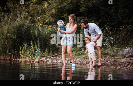 Eine junge Familie mit 2 Kleinkind Kinder die Zeit draußen am Fluss im Sommer. Stockfoto