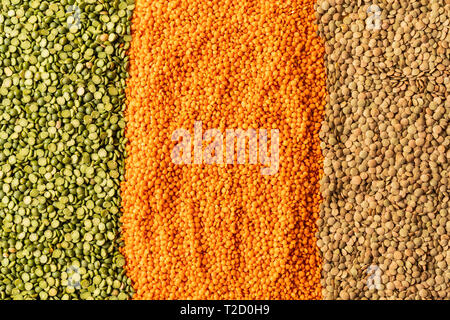 Hintergrund mit kleinen orange, gelbe und grüne Linsen Samen der jährlichen Legumen plant, sie sind reich an pflanzlichen Proteinen. Stockfoto