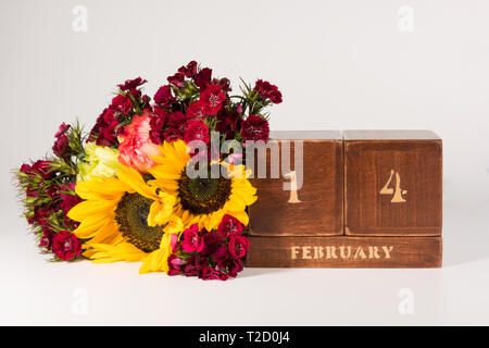 Happy Valentine's Day vintage Holz- Ewiger Kalender für Februar 14 isoliert auf weißem Hintergrund und ein Bündel von verschiedenen Blumen Stockfoto