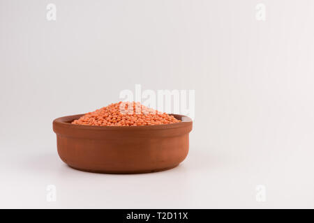 Rote Linsen in Ton Platte auf weißem Hintergrund Stockfoto