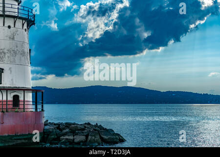 Blick über den Hudson River nach Jersey Shore mit dem Sleepy Hollow Leuchtturm auf der linken Seite, Sonnenstrahlen durch die Wolken brechen Stockfoto