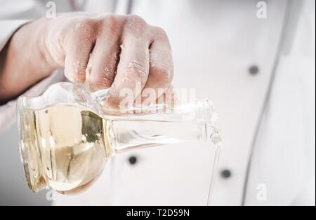 Kaukasische Küche Küchenchef mit nativem Olivenöl in einer Küche. Restaurants und Dinning Industrie Stockfoto