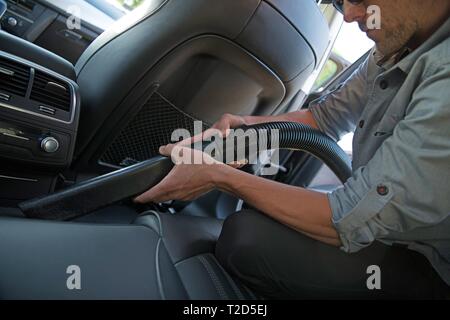 Kaukasischen Männern in seinem 30s Staubsaugen Hat ein modernes Auto. Die regelmäßige Wartung der Fahrzeuge. Stockfoto