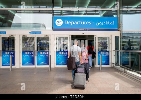 Passagiere mit rollenden Fälle in der Abflughalle auf dem Internationalen Flughafen von Dubai in den Vereinigten Arabischen Emiraten Stockfoto