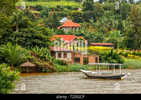 Dach Boot an der Küste mit ruandischen Dorf im Hintergrund verankert, Kivu See, Ruanda Stockfoto