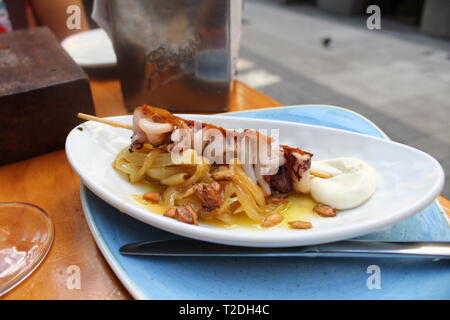 Gegrillter Tintenfischspieß mit Sauce und Aioli, ein modernes Pintxo, serviert auf einer Terrasse in Bilbao, Spanien Stockfoto
