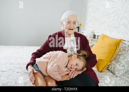 Glückliche Momente mit ihrer Urgroßmutter, ältere Dame viel Zeit mit ihrem großen Enkelin. Restless freche kleine Mädchen ein Nickerchen auf dem gre Stockfoto