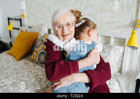 Glückliche Momente mit ihrer Urgroßmutter, ältere Dame viel Zeit mit ihrem großen Enkelin. Happy hug Stockfoto