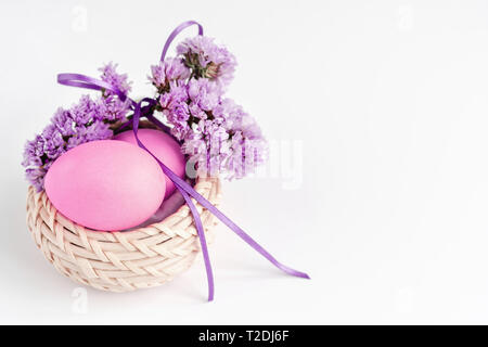 Ostern Zusammensetzung der Eier im Korb mit Blumen in lila Tönen auf weißem Hintergrund eingerichtet. Grußkarte. Kopieren Sie Platz. Stockfoto