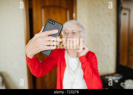 Gut gekleidet Grauhaariger fancy Senior Frau macht selfie in Ihr Schlafzimmer. Stockfoto