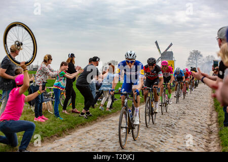 Templeuve, Frankreich - April 08, 2018: Das peloton Reiten auf der gepflasterten Straße in Templeuve vor der traditionellen Vertain Windmühle in Paris - Stockfoto