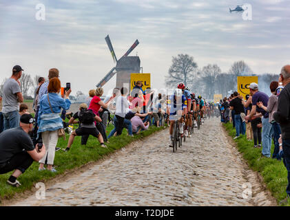 Templeuve, Frankreich - April 08, 2018: Das peloton Reiten auf der gepflasterten Straße in Templeuve vor der traditionellen Vertain Windmühle in Paris - Stockfoto