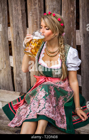 Hübsche junge deutsche Oktoberfest blonde Frau in einem Dirndl Kleid mit Bier Stockfoto