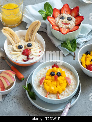 Lustige Schüsseln mit Haferflockenbrei mit Häschen, Küken und Blume für Ostern Stockfoto