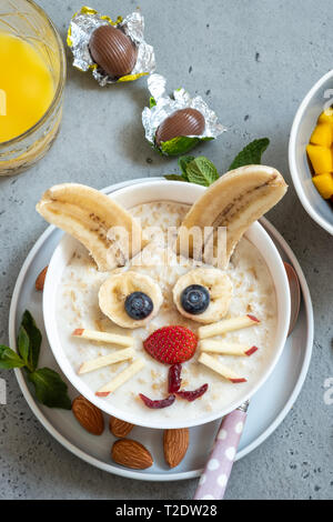 Lustige Schüsseln mit Haferflockenbrei mit Häschen, Küken und Blume für Ostern Stockfoto