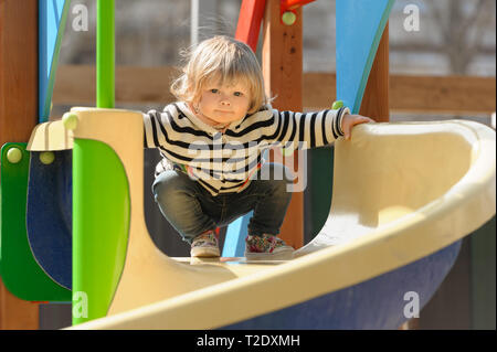 Süße kleine blonde Kleinkind Mädchen Rutschen für die Kinder am Spielplatz schieben Stockfoto