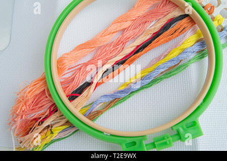 Embroidery Hoop mit Leinwand und hellen Nähfäden für Tabelle Stickerei auf weißem Hintergrund, Ansicht von oben. Stockfoto