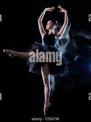 Eine kaukasische junge Frau ballerina Tänzerin tanzen auf schwarzen Hintergrund mit Licht malen motion blur-Effekt isoliert Stockfoto
