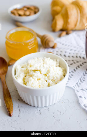 Gesundes Frühstück mit Quark oder Ricotta mit Mandeln Nüsse, Honig und Tasse Kaffee mit Milch auf weißen alten Holztisch, kopieren Raum , ea Stockfoto