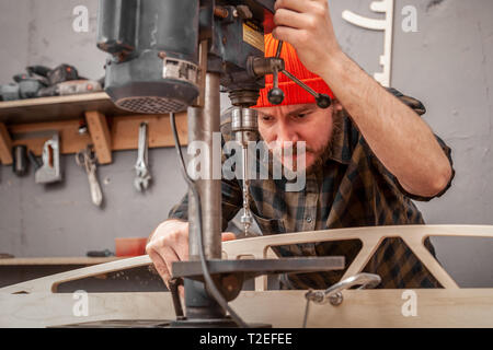 Tischler Bohrer ein Loch mit einer elektrischen Bohrmaschine Holzbrett. Holz bohren Bohrer in der Hand bohren Loch in Holz- ba Stockfoto