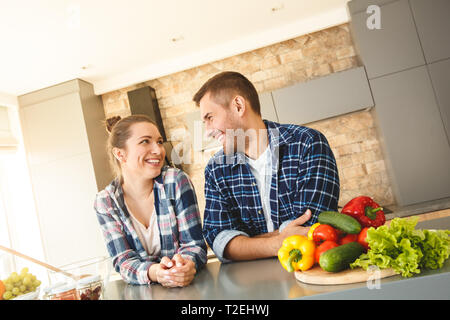 Der Mann und die Frau zu Hause gestützt auf Tisch in der Küche zusammen, sich einander reden lachen Freude Stockfoto