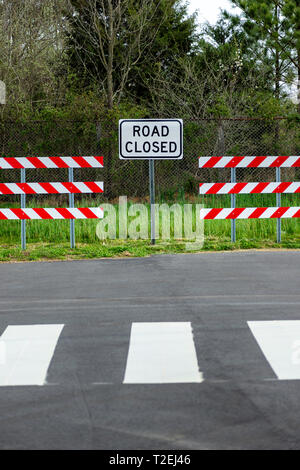 Vertikale Schuß von zwei rot-weiß gestreifte Schranken mit einer Straße geschlossen Zeichen in der Mitte von Ihnen. Stockfoto