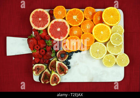 Bunte Obstplatte Montage mit regenbogen farbe Obst einschließlich Zitrusfrüchte, Beeren, Feigen und Kiwis auf weißem Marmor mit kopieren. Stockfoto