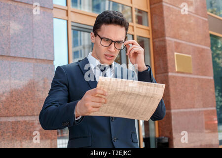 Young Business Mann Tragen von Brillen auf der Stadt Straße an der Zeitung Stockfoto