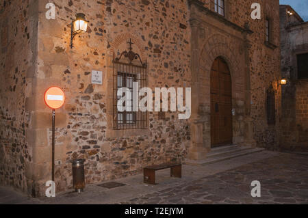 Fassade mit Holztür, vergitterten Fenster und Verkehrszeichen in der Dämmerung in Caceres. Eine charmante Stadt mit einem vollständig erhaltenen Altstadt in Spanien. Stockfoto