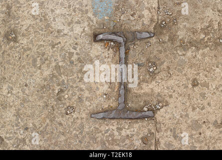 Detail aus Gusseisen Nummer Eins oder die Buchstaben I auf rauen Beton Boden Stockfoto