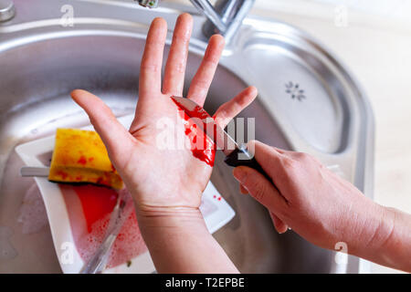 Eine Frau schneidet sich mit einem Messer in der Küche Stockfoto