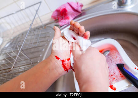 Eine Frau schneidet sich mit einem Messer in der Küche Stockfoto