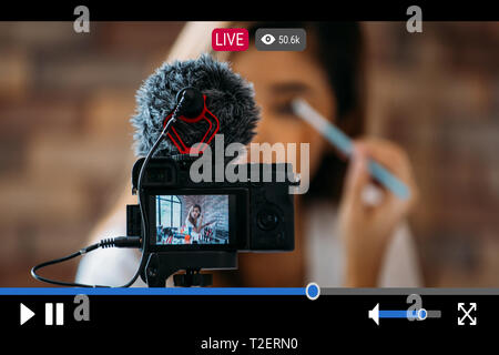 Junge schöne Frau Recording Live Stream Video für Make-up und Kosmetik Geschäftszweck online mit Video player Schnittstelle Stockfoto