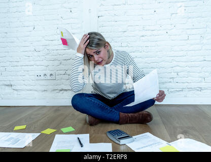 Portrait von sorgen junge Frau Gefühl gestresst und verzweifelt auf den Boden mit Taschenrechner Rechnungslegung Aufwendungen, die nicht in der Lage, Hypothek zu zahlen. Bei der Bezahlung d Stockfoto