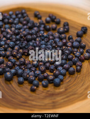 Ein Haufen von Wacholderbeeren ganz nah auf unfocused Holz- Hintergrund. Stockfoto