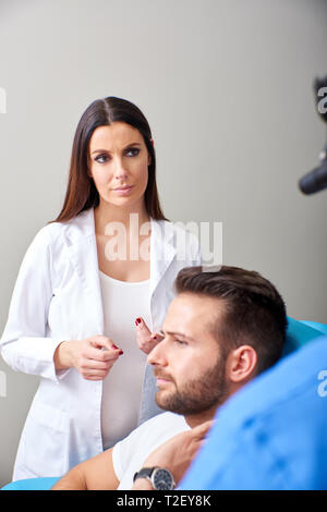 Eine schöne Assistant und einen stattlichen Arzt Beratung über Patienten im Krankenhaus. Stockfoto