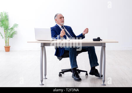 Alter Geschäftsmann Yoga Übungen im Büro Stockfoto