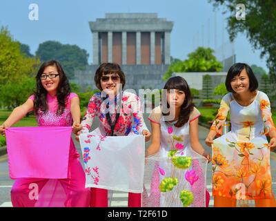 Vier kostümierte Vietnamesische Mädchen wave mit den Schwänzen ihrer traditionellen vietnamesischen Seidenkleider (Áo dài) vor Hanoi Ho Chi Minh Mausoleum. Stockfoto