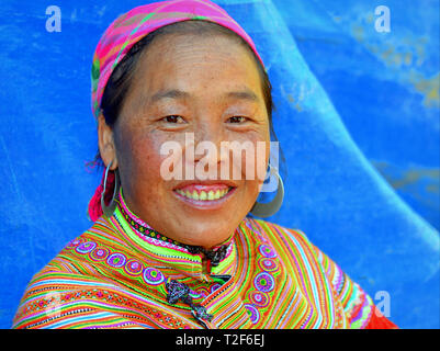 Im mittleren Alter vietnamesischen Blume H'mong Frau trägt eine bunte gestickte traditionelle Blume H'mong Kostüm mit großen tribal Silber Ohrringe. Stockfoto