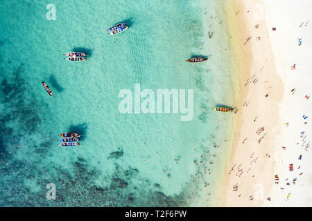 Ansicht von oben, aus der Vogelperspektive einen wunderschönen tropischen Strand mit weißem Sand und türkisfarbenem Wasser, long tail Boote und Menschen zu sonnen. Stockfoto