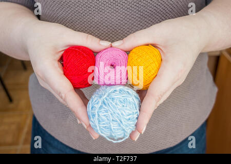 stitching, yarn, ingrain, thread in female hands in heart shaped. materials for handmade and handiwork - sewing, embroidery, knitting. small balls Stockfoto