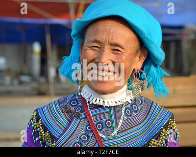 Ältere Vietnamesischen blau H'Mong Bergvolk Frau mit drei Gold Zähne trägt traditionelle H'Mong Stickerei in Blau und Lächeln für die Kamera. Stockfoto